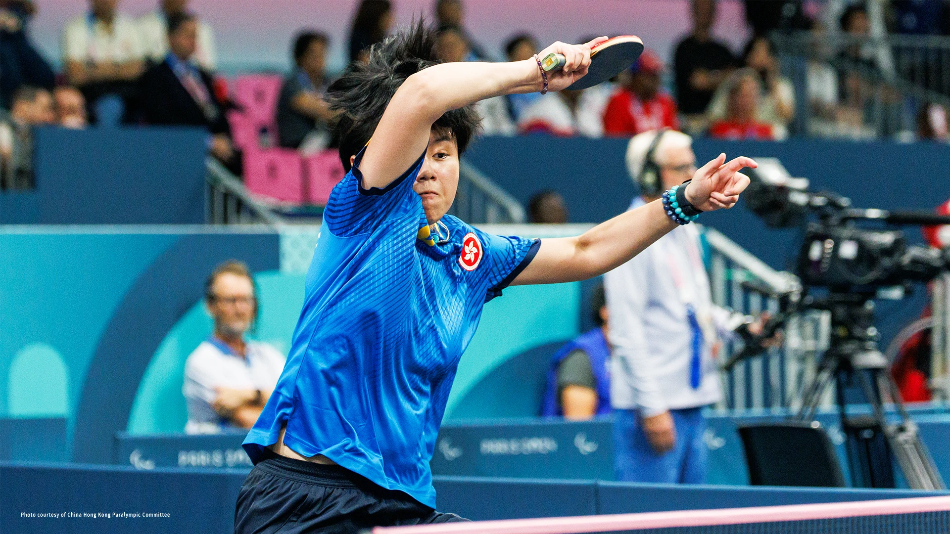 A woman in a table tennis uniform striking the ping pong ball.